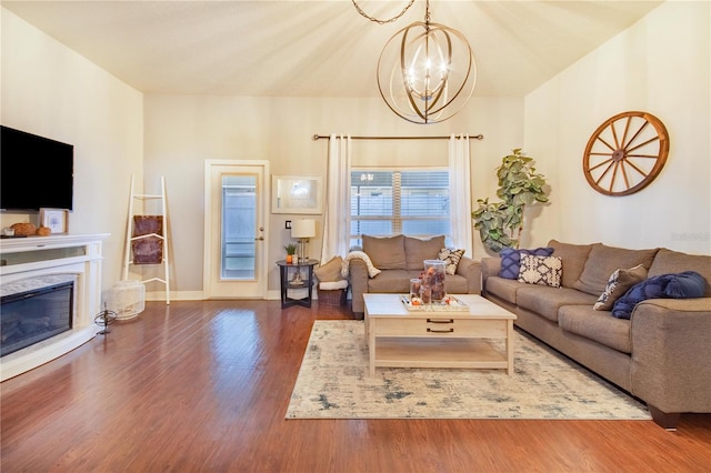 living room with dark hardwood / wood-style flooring, a chandelier, and a fireplace