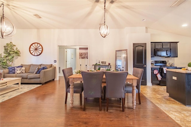 dining area with a chandelier, lofted ceiling, and wood-type flooring