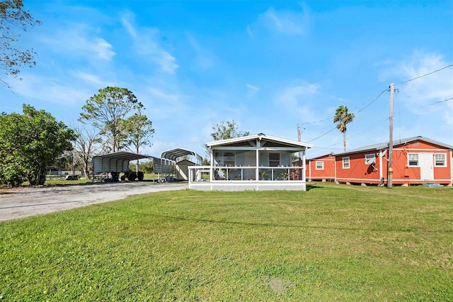 exterior space featuring a carport, a sunroom, a storage shed, and a lawn