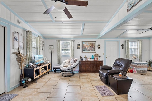 living area with ceiling fan, beamed ceiling, and light tile patterned floors