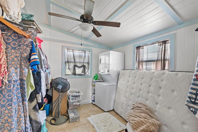 laundry area featuring ceiling fan, wooden ceiling, wooden walls, light tile patterned flooring, and stacked washer and clothes dryer