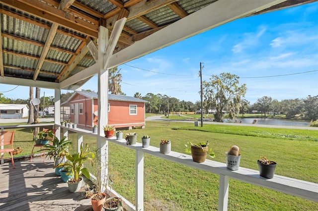 exterior space featuring a deck with water view and a storage unit