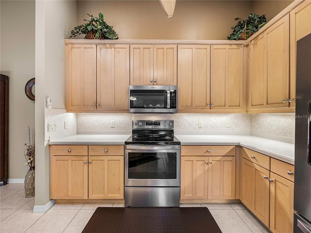 kitchen featuring stainless steel appliances, light brown cabinetry, decorative backsplash, and light tile patterned floors