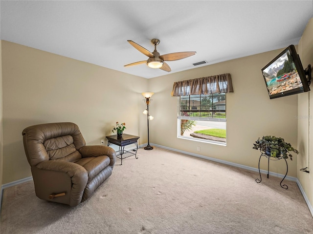 living area with ceiling fan and carpet