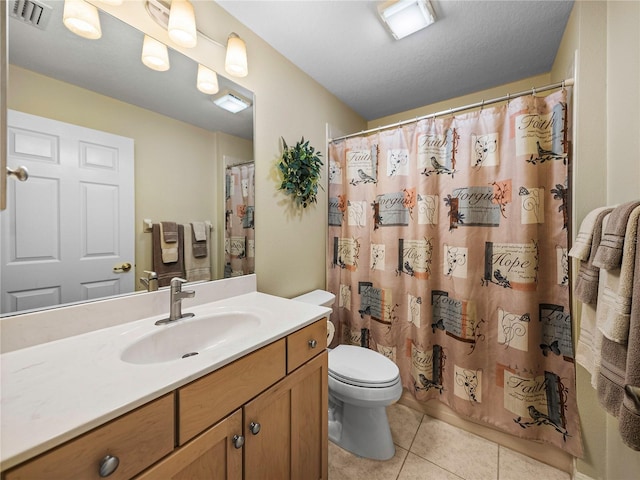 bathroom featuring tile patterned flooring, vanity, toilet, and walk in shower