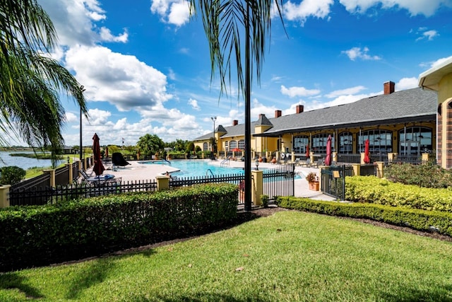 view of swimming pool featuring a lawn, a patio, and a water view