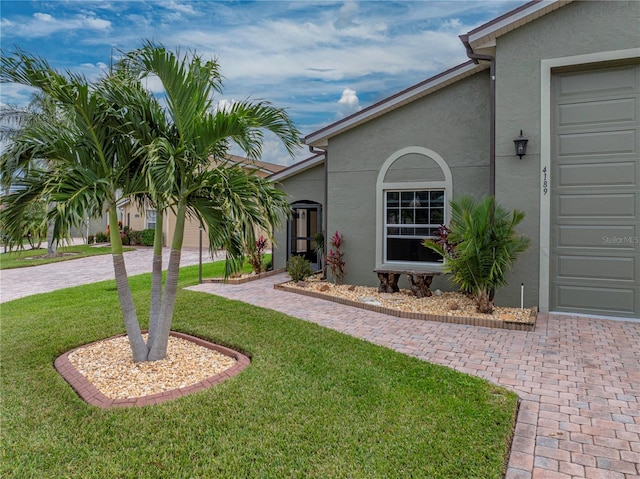 view of exterior entry with a garage and a lawn