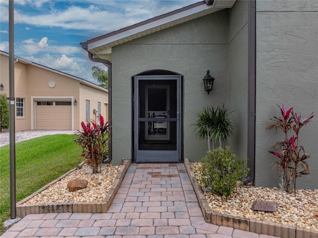 doorway to property with a garage and a yard