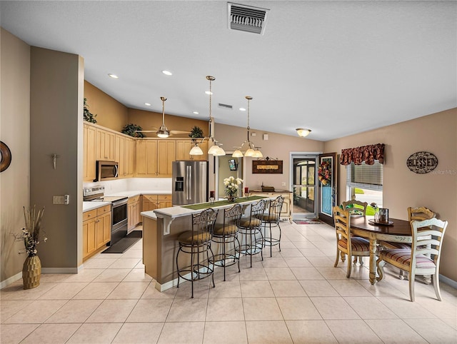 kitchen featuring a center island, light tile patterned floors, light brown cabinets, pendant lighting, and stainless steel appliances