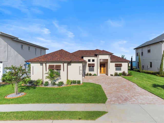 193 Stargrass Dr, Auburndale, FL 33823 - view of front of home with a front yard, decorative driveway, stucco siding, and a shingled roof