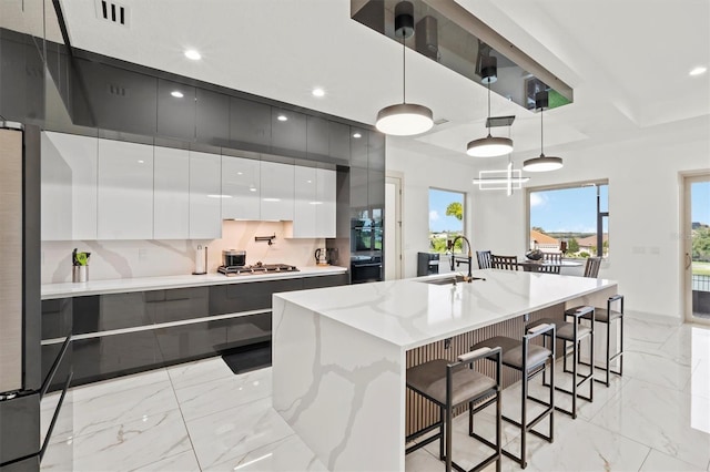 193 Stargrass Dr, Auburndale, FL 33823 - kitchen featuring modern cabinets, a sink, light marble finish floors, white cabinetry, and a breakfast bar area