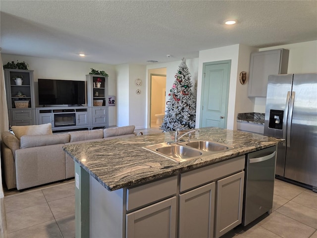 kitchen featuring stainless steel appliances, a textured ceiling, gray cabinets, sink, and a kitchen island with sink