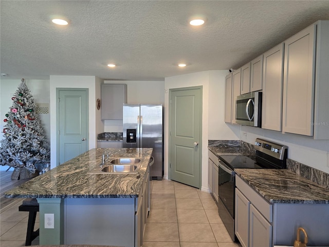 kitchen featuring gray cabinets, appliances with stainless steel finishes, sink, and a center island with sink