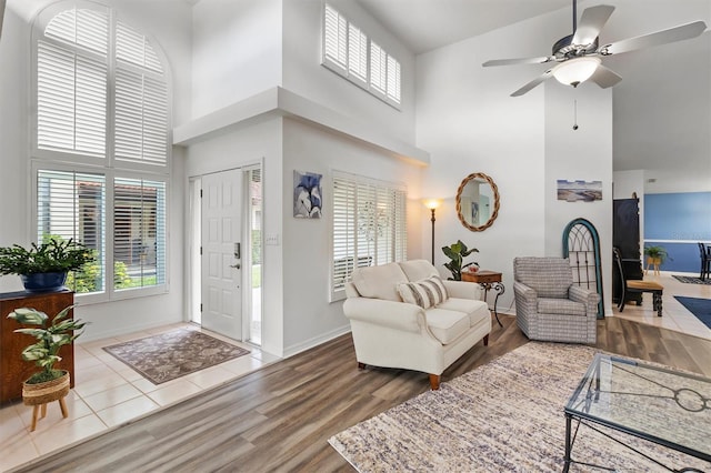 living room featuring a towering ceiling, ceiling fan, and hardwood / wood-style flooring