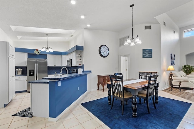 kitchen featuring appliances with stainless steel finishes, decorative light fixtures, a chandelier, white cabinetry, and light tile patterned flooring