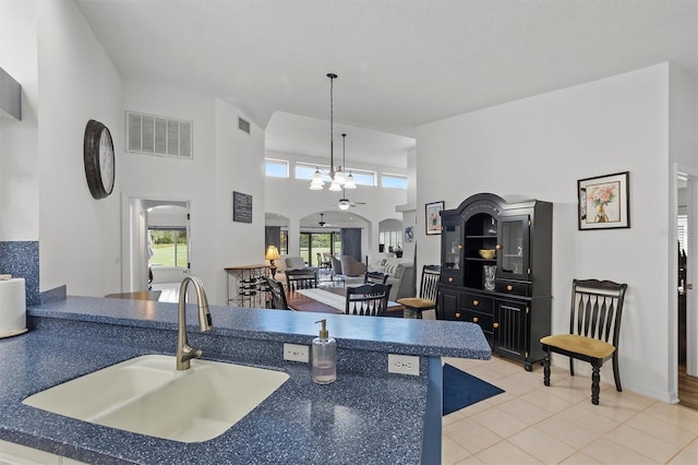 kitchen featuring sink, an inviting chandelier, a towering ceiling, pendant lighting, and light tile patterned flooring