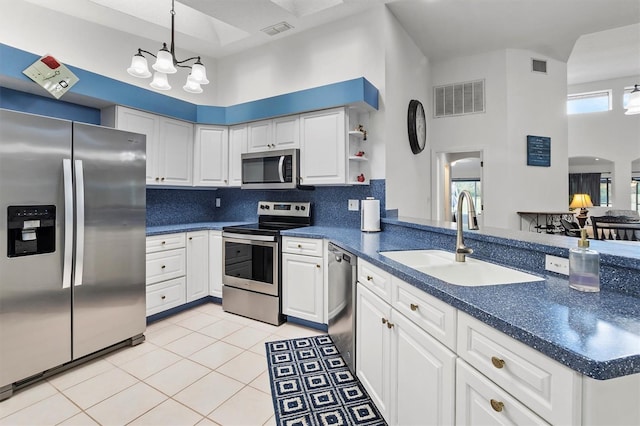 kitchen featuring a high ceiling, stainless steel appliances, white cabinetry, and sink