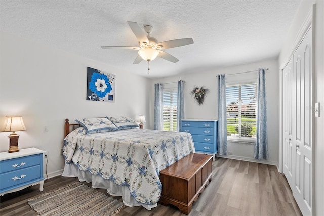 bedroom featuring hardwood / wood-style floors, a textured ceiling, a closet, and ceiling fan