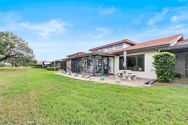 rear view of property featuring a patio area, a sunroom, and a yard