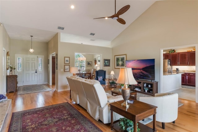 living room featuring ceiling fan, light hardwood / wood-style flooring, and high vaulted ceiling