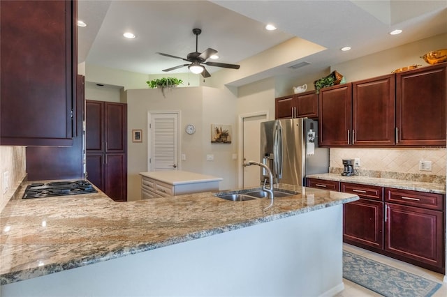 kitchen featuring kitchen peninsula, sink, ceiling fan, backsplash, and appliances with stainless steel finishes