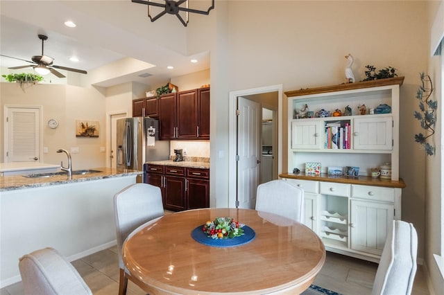 tiled dining room with a high ceiling, ceiling fan, and sink