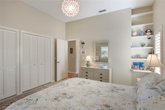 bedroom with a chandelier, multiple windows, and multiple closets