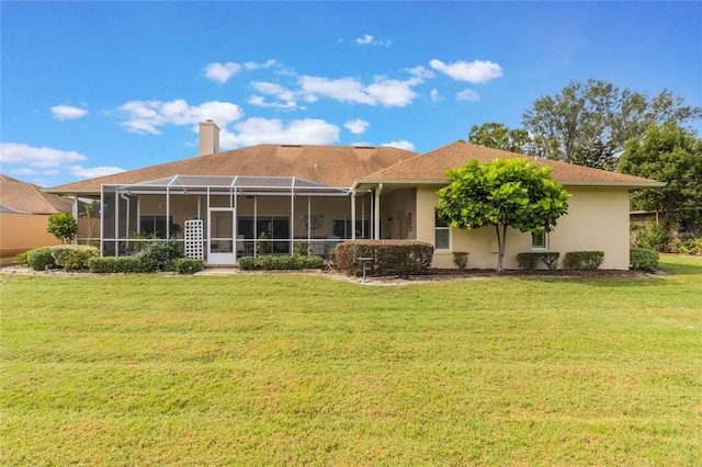 rear view of property with a lanai and a yard