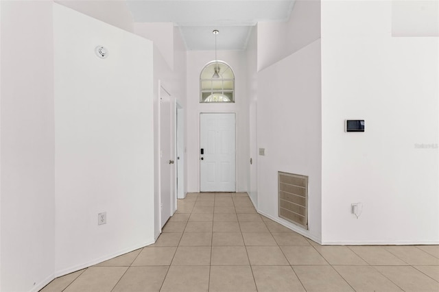 hallway featuring a towering ceiling and light tile patterned floors