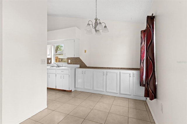 kitchen with white cabinets, light tile patterned floors, pendant lighting, and vaulted ceiling