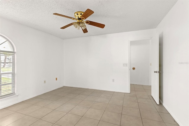 tiled empty room featuring ceiling fan and a textured ceiling