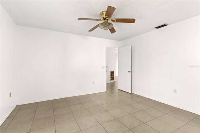 empty room with a textured ceiling, light tile patterned floors, and ceiling fan