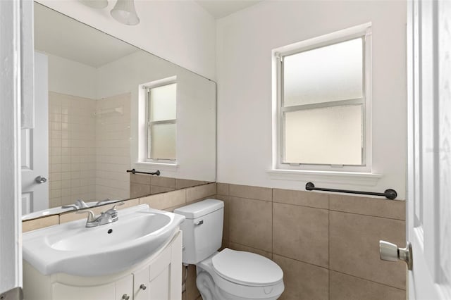 bathroom with vanity, toilet, and tile walls