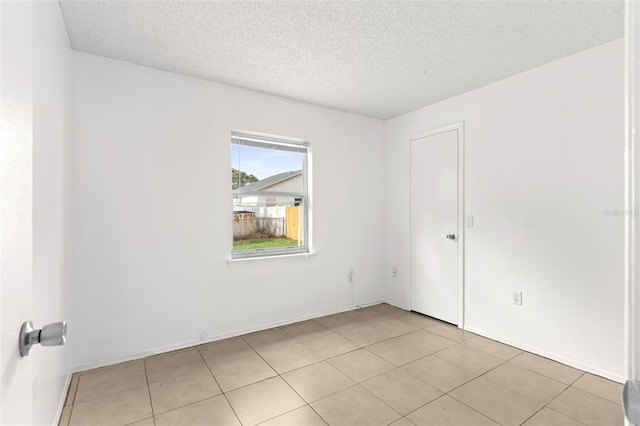 unfurnished room with a textured ceiling and light tile patterned floors