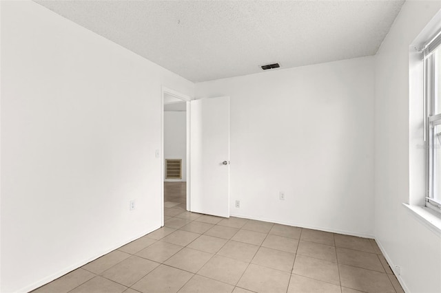 tiled empty room featuring a healthy amount of sunlight and a textured ceiling