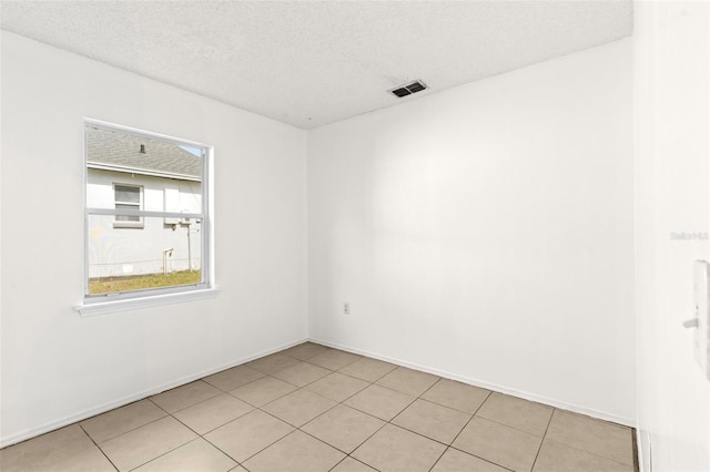 spare room featuring a textured ceiling and light tile patterned flooring