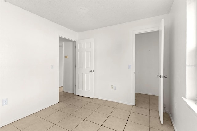 unfurnished bedroom featuring a textured ceiling and light tile patterned flooring