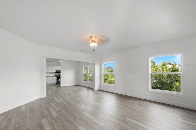 unfurnished living room featuring ceiling fan, a healthy amount of sunlight, and light hardwood / wood-style flooring