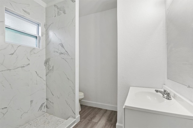 bathroom featuring tiled shower, vanity, hardwood / wood-style flooring, and toilet