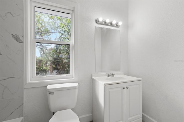 bathroom with toilet, vanity, and tiled shower