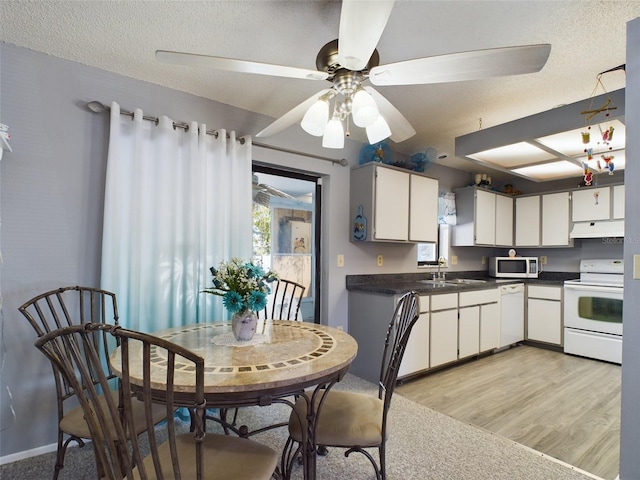 kitchen featuring white cabinets, a textured ceiling, sink, light wood-type flooring, and white appliances