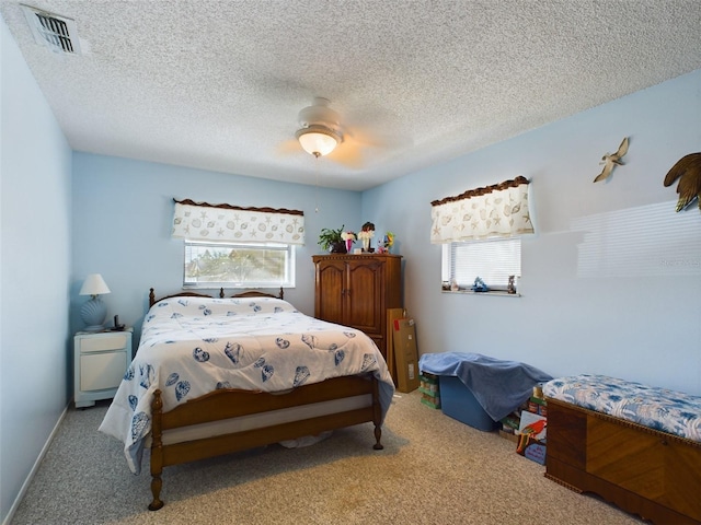 carpeted bedroom with ceiling fan, multiple windows, and a textured ceiling