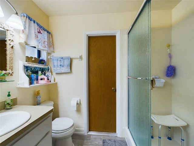 bathroom featuring walk in shower, wood-type flooring, toilet, and vanity