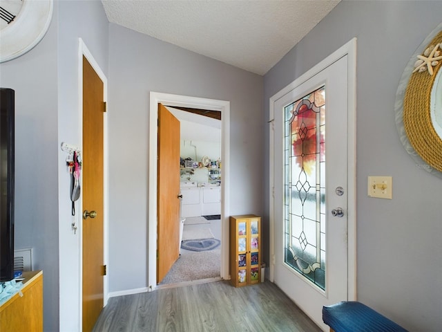 foyer featuring hardwood / wood-style floors, vaulted ceiling, and a textured ceiling