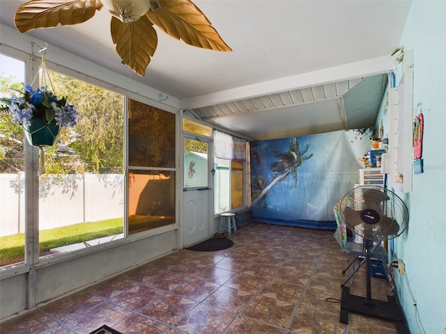 unfurnished sunroom with a wealth of natural light, beamed ceiling, and ceiling fan