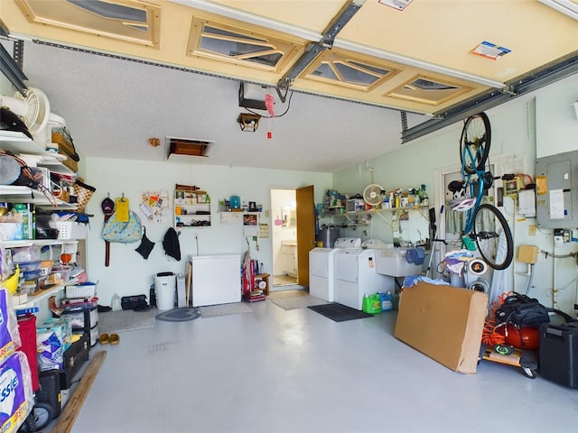 garage featuring electric panel, a garage door opener, and separate washer and dryer