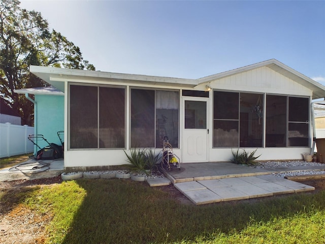 back of house featuring a patio, a sunroom, and a lawn