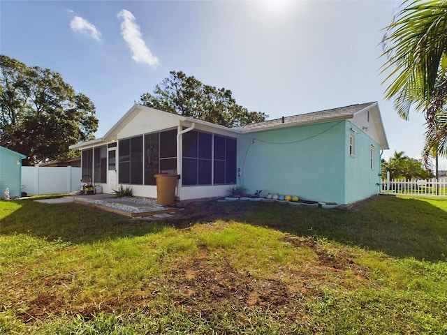 back of property featuring a lawn and a sunroom