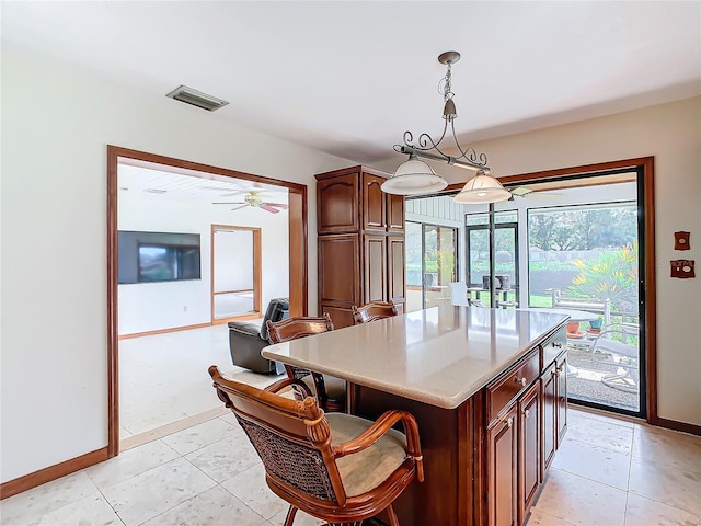 kitchen featuring a center island, light tile patterned floors, pendant lighting, and ceiling fan with notable chandelier