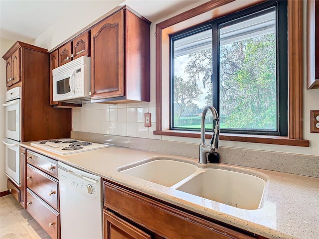 kitchen featuring light stone countertops, white appliances, plenty of natural light, and sink